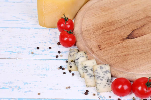 Different types of cheese with empty board on table close-up — Stock Photo, Image