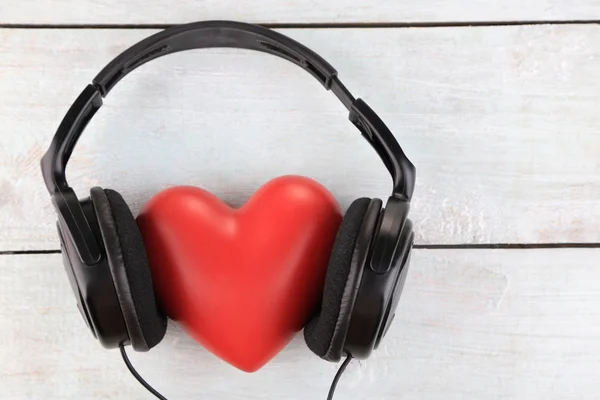 Auriculares y corazón sobre fondo de madera — Foto de Stock