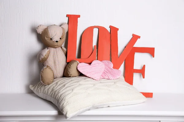 Letras decorativas formando palavra AMOR com ursinho de pelúcia no fundo da parede — Fotografia de Stock