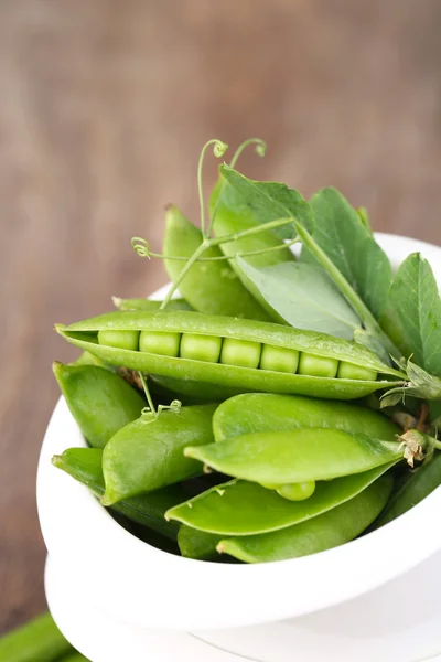 Fresh green peas in bowl on wooden table — Stock Photo, Image