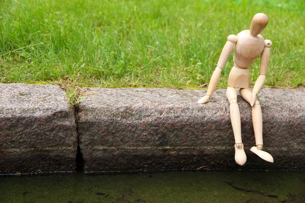 Títere de pose de madera sentado en piedra, al aire libre —  Fotos de Stock