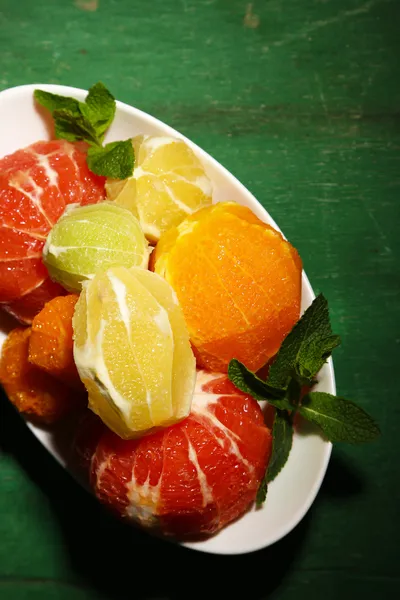 Citrus fruits without skin, on plate, on wooden background — Stock Photo, Image