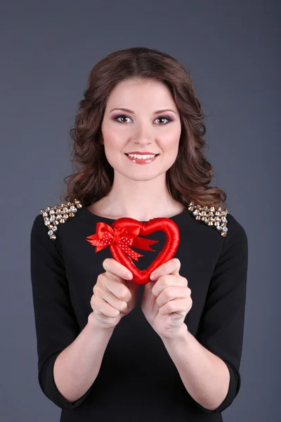 Hermosa joven en vestido con corazón sobre fondo gris —  Fotos de Stock