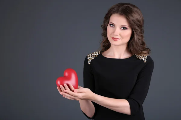 Belle jeune fille en robe avec coeur sur fond gris — Photo