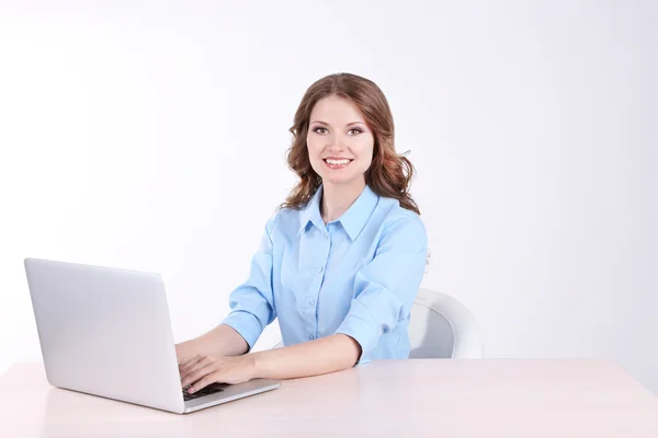 Jovem mulher de negócios sentada à mesa com notebook no quarto — Fotografia de Stock