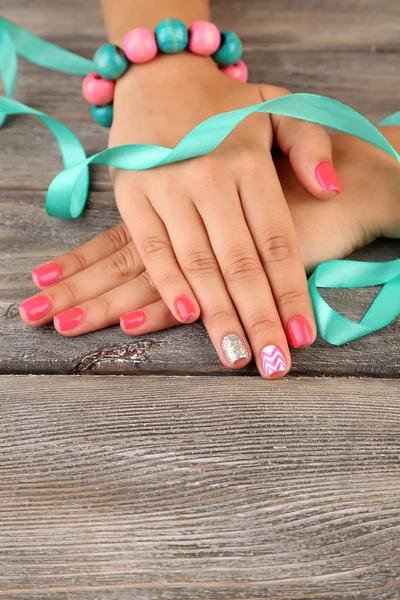 Kvinnlig hand med eleganta färgstarka naglar, på trä bakgrund — Stockfoto