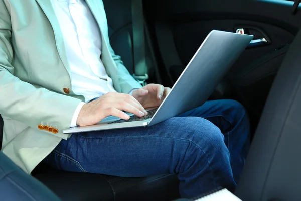 Hombre sentado en el coche con portátil — Foto de Stock