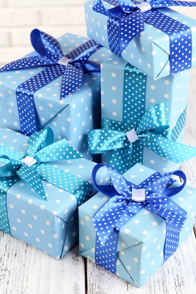 Beautiful gifts on table on brick wall background — Stock Photo, Image