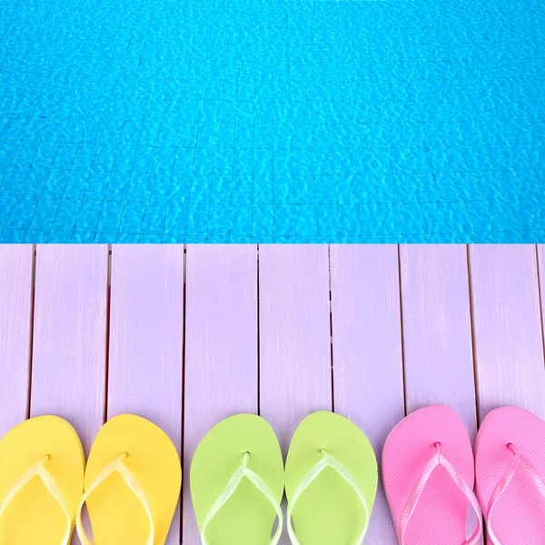 Infradito colorate sulla piattaforma di legno accanto al mare — Foto Stock