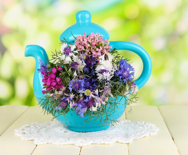 Schöner Strauß in blauer Teekanne auf Holztisch auf natürlichem Hintergrund — Stockfoto