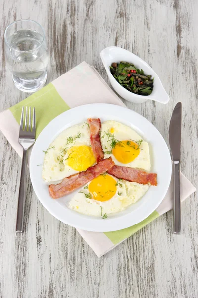 Huevos revueltos y tocino en plato sobre servilleta sobre mesa de madera —  Fotos de Stock