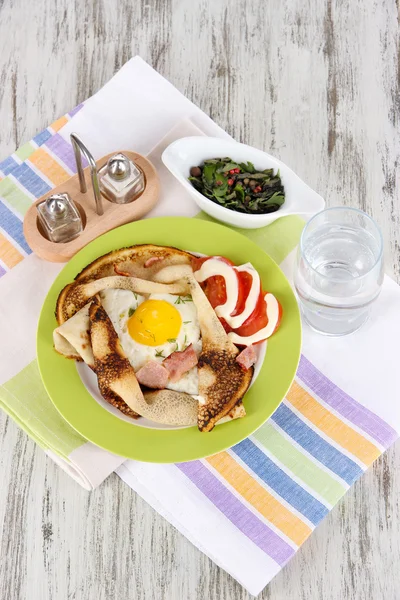 Huevos revueltos y tortitas en plato sobre servilleta sobre mesa de madera —  Fotos de Stock