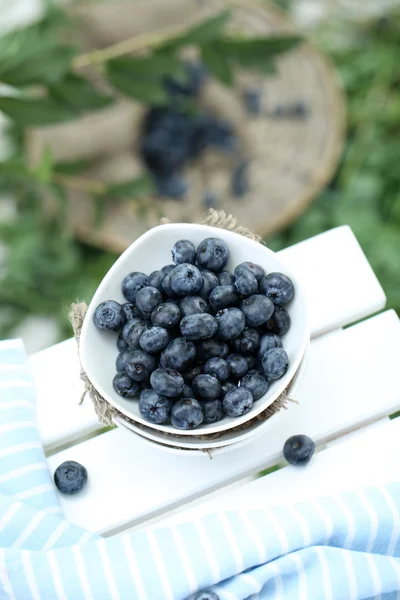 Blueberries in plates near napkin on wooden table on grass background — Stock Photo, Image