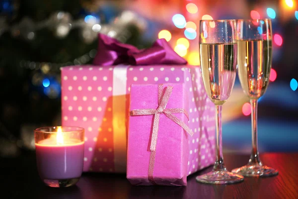 De nombreux cadeaux et une coupe de champagne sur fond lumineux — Photo
