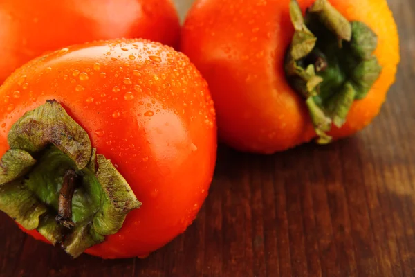 Rijpe persimmons op houten ondergrond — Stockfoto