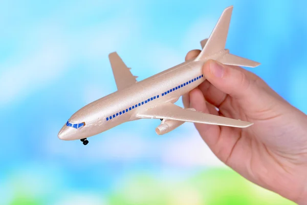 Toy airplane in hand on light blue background — Stock Photo, Image