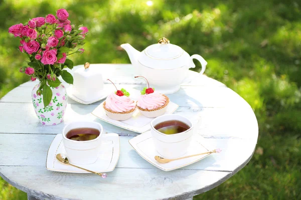 Mesa com xícaras de chá e bolos saborosos — Fotografia de Stock