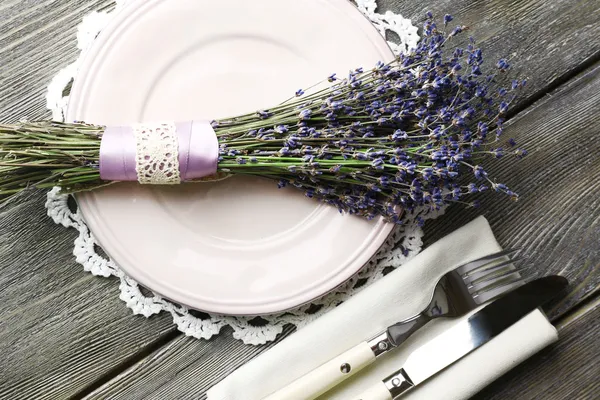 Ahşap masa arka plan üzerinde lavanta çiçekleri ile yemek masası ayarı — Stok fotoğraf