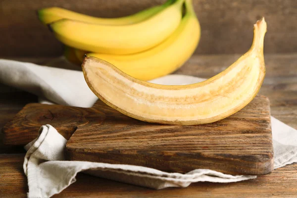 Plátanos cortados a la mitad y maduros sobre fondo de madera —  Fotos de Stock