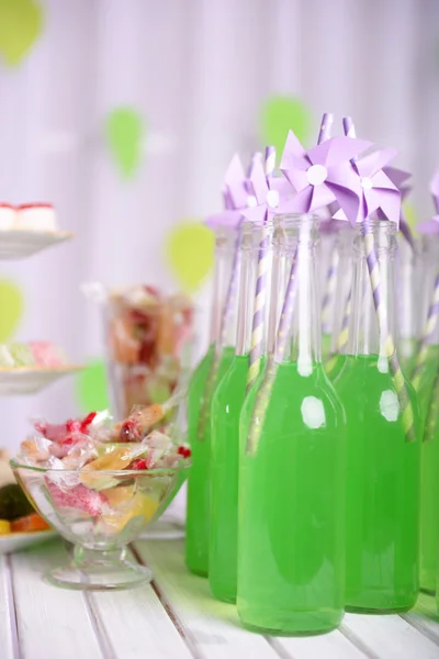 Botellas de bebida con paja y dulces sobre fondo decorativo —  Fotos de Stock