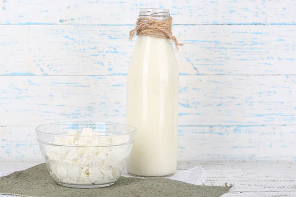 Glass bottle of milk and cottage cheese on wooden background — Stock Photo, Image