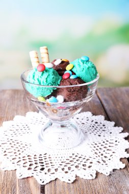 çok renkli şekerler ve gofret çikolata dondurma cam kapta, aydınlık arka plan üzerinde renkli ahşap masa üzerinde rulo