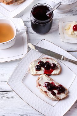 kiraz reçeli ve ahşap zemin üzerinde plaka üzerinde ev yapımı tereyağı ile taze ekmek