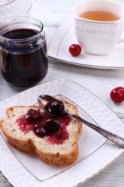kiraz reçeli ve ahşap zemin üzerinde plaka üzerinde ev yapımı tereyağı ile taze ekmek