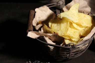 lezzetli patates cipsi ile koyu ahşap masa üzerinde metal sepet içinde