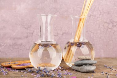 Spa natürmort lavanta yağı ve pembe bir arka plan üzerinde ahşap masaya çiçek