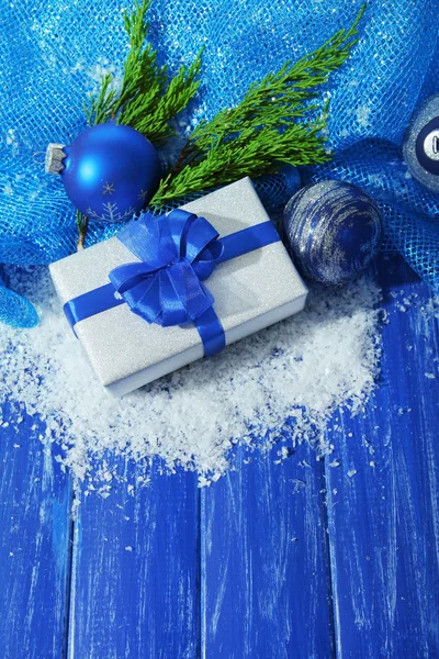 Sammansättning med julen bollar, presentförpackning och snö på färg trä bakgrund — Stockfoto