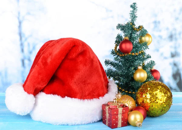 明るい背景にテーブルの上のクリスマスの装飾とクリスマス帽子 — ストック写真