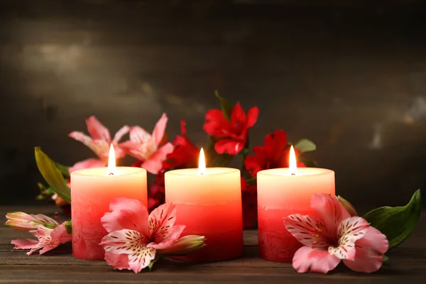 Belas velas com flores na mesa de madeira, no fundo escuro — Fotografia de Stock