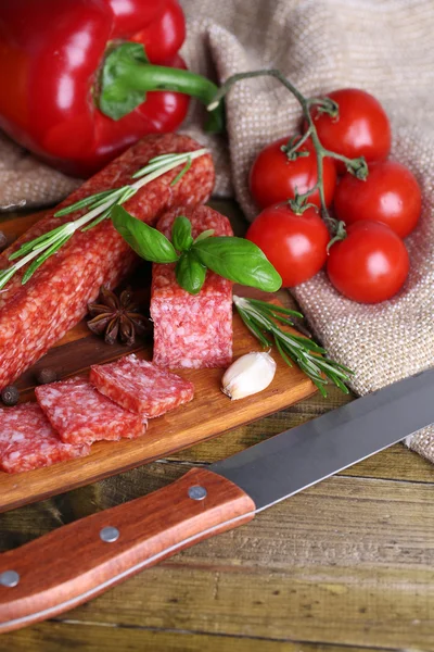 Leckere Salamiwurst und Gewürze auf Holzgrund — Stockfoto