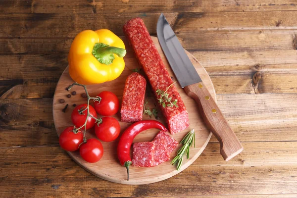 Leckere Salamiwurst und Gewürze auf Holzgrund — Stockfoto