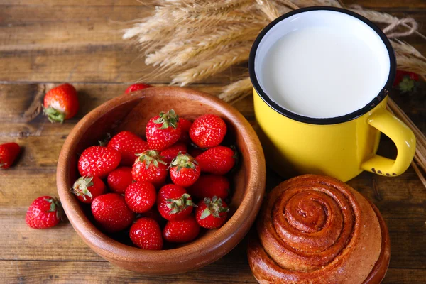 Fraises douces mûres, pain frais et tasse avec du lait sur fond de bois de couleur — Photo