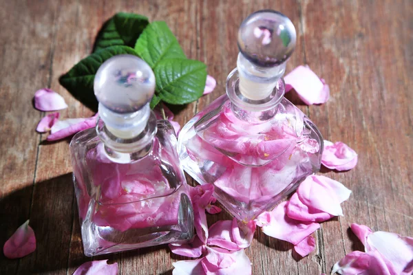 Huile de rose en bouteilles sur fond de bois couleur — Photo