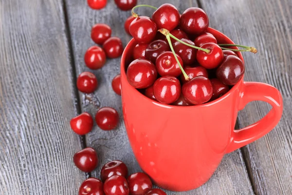 Sweet cherries in mug on wooden background — Stock Photo, Image