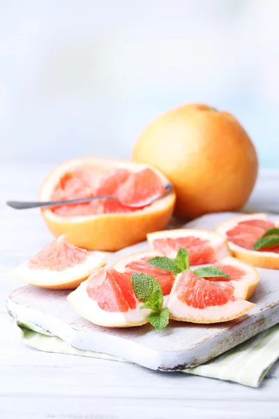 Pomelos maduros sobre tabla de cortar, sobre mesa de madera, sobre fondo claro — Foto de Stock