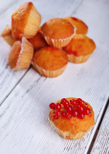 Leckeres Muffin mit roten Johannisbeeren auf farbigem Holzhintergrund — Stockfoto