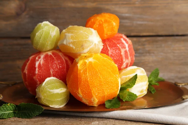 Citrus fruits without skin on tray, on wooden background — Stock Photo, Image