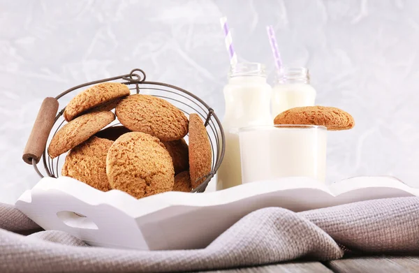 Leche y galletas en la mesa sobre fondo gris claro —  Fotos de Stock