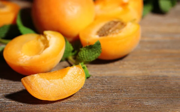 Ripe apricots with green mint leaves on wooden background — Stock Photo, Image