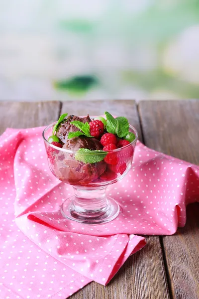 Schokoladeneis mit Minzblättern und reifen Beeren in Glasschale, auf Holztisch, auf hellem Hintergrund — Stockfoto