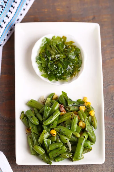 Salade met groene bonen en maïs met saus op plaat, op een houten achtergrond kleur — Stockfoto