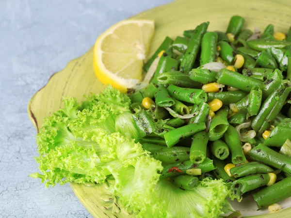 Salade aux haricots verts et maïs, sur assiette, sur fond de bois couleur — Photo