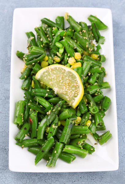 Insalata con fagiolini e mais, semi di sesamo su piatto, su sfondo di legno a colori — Foto Stock