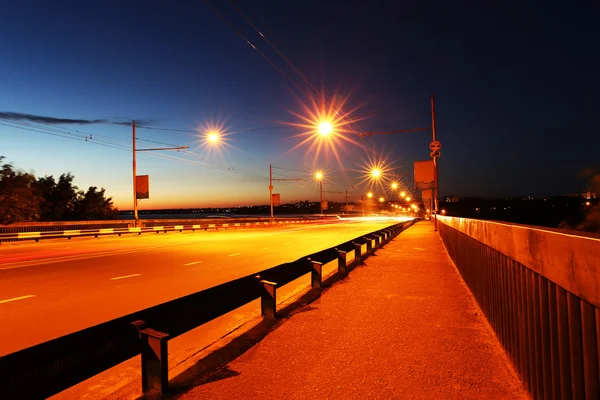 Carro em movimento com luz embaçada pela cidade à noite — Fotografia de Stock