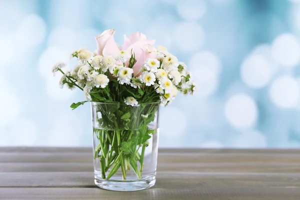 Hermosas flores en la mesa, sobre fondo brillante —  Fotos de Stock