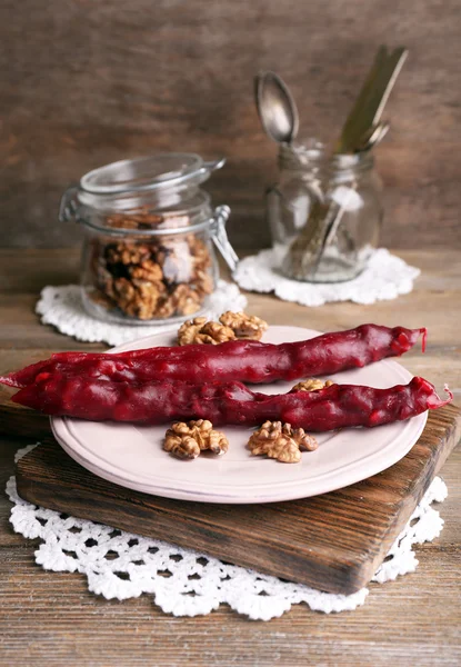 Smakelijke oosterse snoepjes (churchkhela) en verse noten, op houten achtergrond — Stockfoto